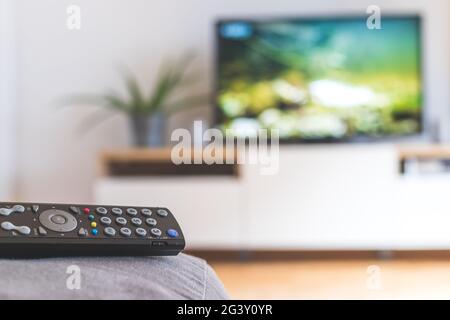 Remote control on the sofa, streaming on a smart TV. Stock Photo