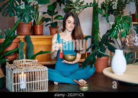 Woman playing on Tibetan singing bowl sitting at home Stock Photo