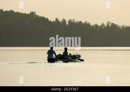 Gambia; Western Region; on the Bintang Bolong; two men sit in a fully loaded boat; drive towards Bintang Stock Photo