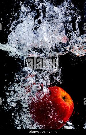 red apple thrown into water with splash and black background. Stock Photo