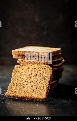 Sliced wholegrain bread on black table. Stock Photo