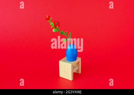 Toy flower on wooden chair on reg background Stock Photo