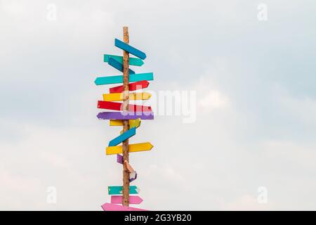 Colorful wooden direction arrow signs on a wooden pole Stock Photo