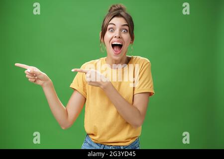 Waist-up shot of enthusiastic and charismatic impressed happy girl laughing and smiling broadly pointing left at funny hilarious Stock Photo