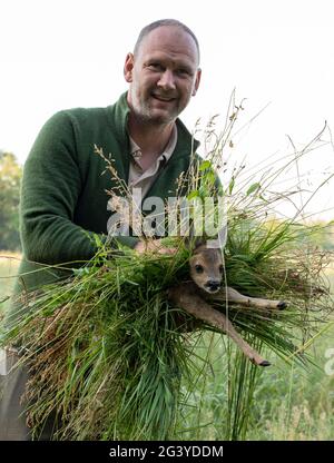 Magdeburg, Germany. 17th June, 2021. Wilko Florstedt from the association Wildtierretter Sachsen-Anhalt carries a fawn from a field. It was previously tracked with a drone equipped with a thermal imaging camera. In this way, fawns are protected from being killed by the mower of large agricultural machinery. According to its own information, the association Wildtierretter Sachsen-Anhalt has already saved 200 fawns from an agonizing death this year. Credit: Stephan Schulz/dpa-Zentralbild/ZB/dpa/Alamy Live News Stock Photo