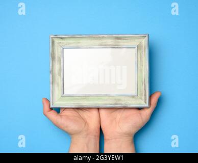 Two female hands holding a rectangular blank wooden frame Stock Photo