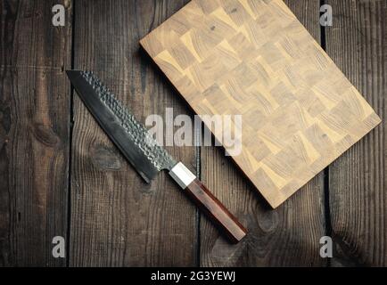 Metal kitchen knife and wooden cutting board on a table made of brown wooden boards Stock Photo