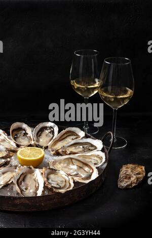 Oysters on a platter, with lemon and wine Stock Photo