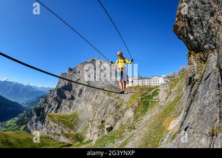 Woman on the Gemmi adventure via ferrata goes over rope bridge, Daubenhorn in the background, Gemmi, Bernese Alps, Valais, Switzerland Stock Photo