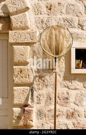 Fishing landing net against the background of a stone wall Stock Photo