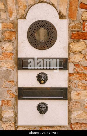 Close-ups of building facades in Venice, Italy. An old vintage intercom and a mailbox on a stone wall. On door where placed this Stock Photo