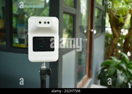 electric temperature measuring machine for virus in front of coffee shop background Stock Photo