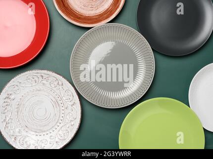 Empty round multicolored ceramic plates on green background Stock Photo