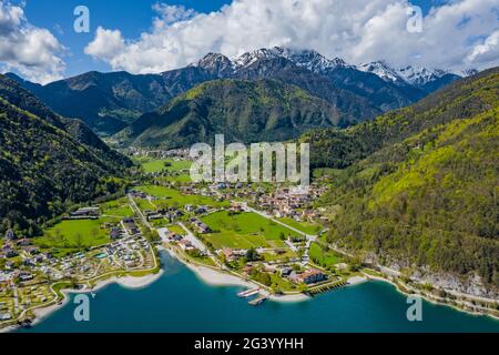 The Improbable aerial landscape of village Molveno, Italy, azure water of lake, empty beach, snow covered mountains Dolomites on Stock Photo