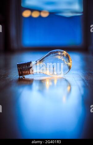 Ideas and innovation: Light bulb with LEDs is lying on the wooden floor. Window and light in the blurry background. Stock Photo