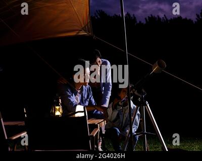 A happy family of three using telescopes outdoors high quality photo Stock Photo