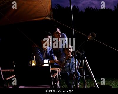 A happy family of three using telescopes outdoors high quality photo Stock Photo