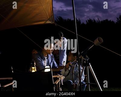 A happy family of three using telescopes outdoors high quality photo Stock Photo