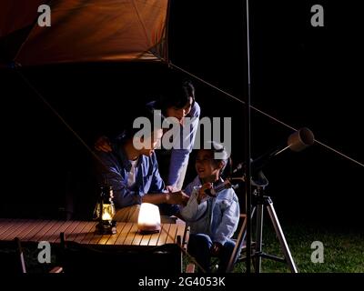 A happy family of three using telescopes outdoors high quality photo Stock Photo