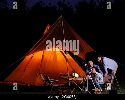 A happy family of three using telescopes outdoors high quality photo Stock Photo