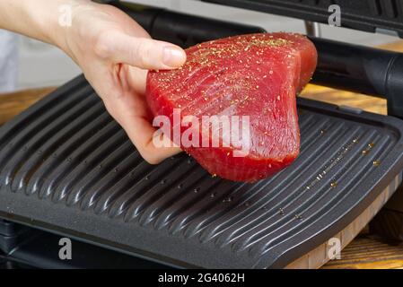 raw tuna steaks cooking on electric grill. Stock Photo