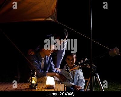 A happy family of three using telescopes outdoors high quality photo Stock Photo