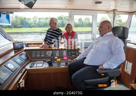 Couple chats with captain on the bridge of the river cruise ship during a cruise on the Rhine, near Andernach, Rhineland-Palatinate, Germany, Europe Stock Photo