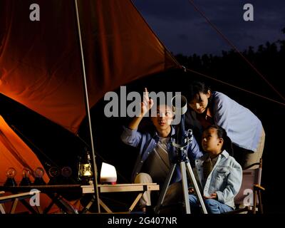 A happy family of three using telescopes outdoors high quality photo Stock Photo