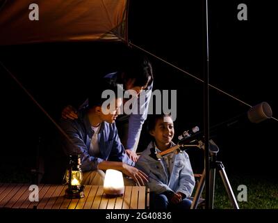 A happy family of three using telescopes outdoors high quality photo Stock Photo