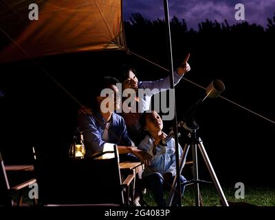 A happy family of three using telescopes outdoors high quality photo Stock Photo