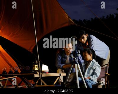 A happy family of three using telescopes outdoors high quality photo Stock Photo