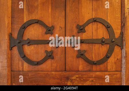 Closeup on vintage, old wooden door with cast iron ornate hinges Stock Photo