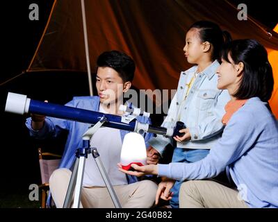 A happy family of three using telescopes outdoors high quality photo Stock Photo