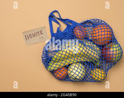 Ripe fresh fruits in a textile string bag on a brown background, top view Stock Photo