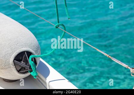 Sailing boat fender on the yacht deck, turquoise blue sea water background, Sailboat bumber closeup, summer cruise in Aegean sea, Greece, copy space, Stock Photo