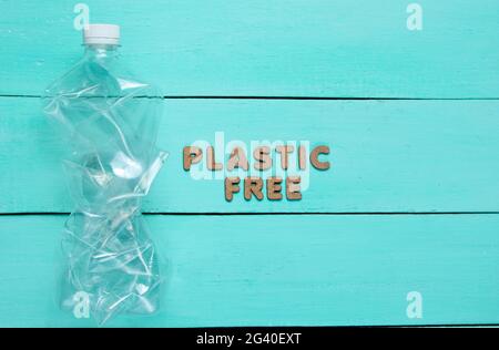 Plastic free concept. Crumpled bottle on a blue wooden background with text plastic free Stock Photo