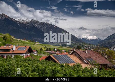 Panorama of solar batteries on roof top, green slopes of the mountains of Italy, Trentino, Dolomites, huge clouds over a valley, Stock Photo