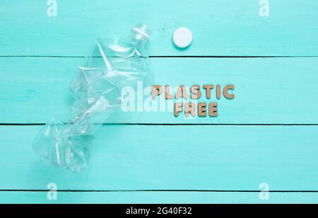 Plastic free concept. Crumpled bottle on a blue wooden background with text plastic free Stock Photo