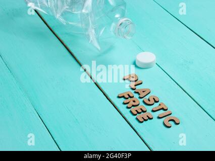 Plastic free concept. Crumpled bottle on a blue wooden background with text plastic free Stock Photo