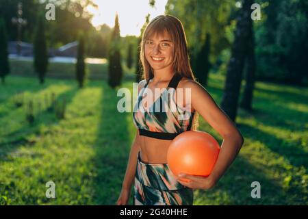Beautiful, sporty girl is engaged in the park with a fitness ball. Cute girl smiling, looking at the camera. Slender girl Stock Photo