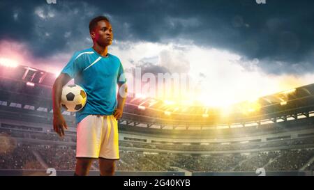 Male african socce, football player standing during sport match on cloudt sky background at stadium Stock Photo