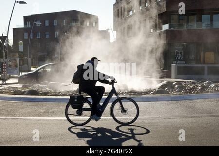 Monheimer Geysir, cyclists at water vapor in the roundabout, Monheim am Rhein, Germany, Europe Stock Photo