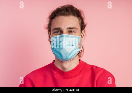 Close up view. Man in a protective mask on a pink background. Concept of protection during a pandemic. Stock Photo
