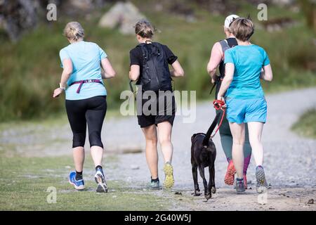 Buttermere, Cumbria, UK. 15 June 2021. Joggers navigate their way around the shore path of Buttermere Lake. Stock Photo