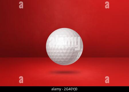 White golf ball on a red studio background Stock Photo