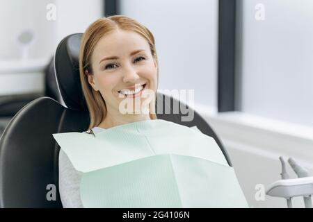 Smiling, positive woman sitting in a dental chair. Beautiful woman waiting for the dentist Stock Photo