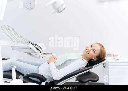 Patient is lying in a dental chair, waiting for the dentist. Attractive woman in the dental office Stock Photo