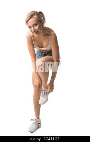 Cheerful young woman tying shoelaces on sneakers Stock Photo