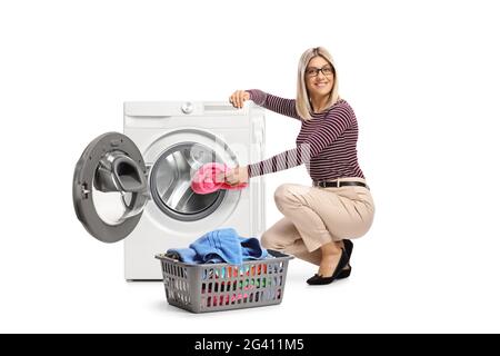 Young woman loading a washing machine isolated on white background Stock Photo