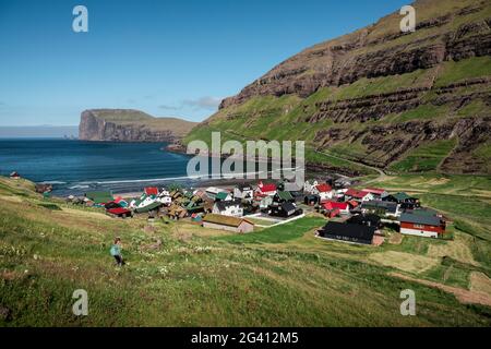 Woman hiking with a view of Tjørnuvík village on Streymoy on Faroe Islands by day Stock Photo